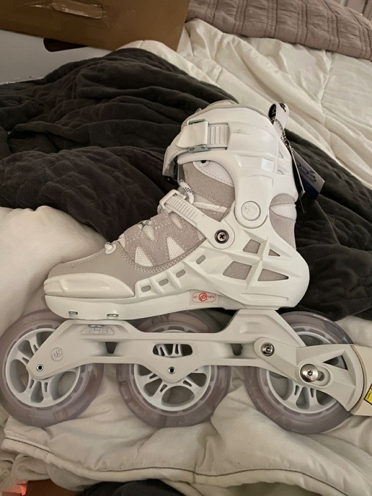 a pair of white roller skates sitting on top of a bed next to a pillow