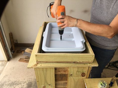 a woman is using a drill to attach the top of a wooden box with an orange screwdriver