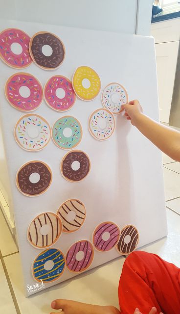 a little boy sitting on the floor next to a white board with doughnuts on it