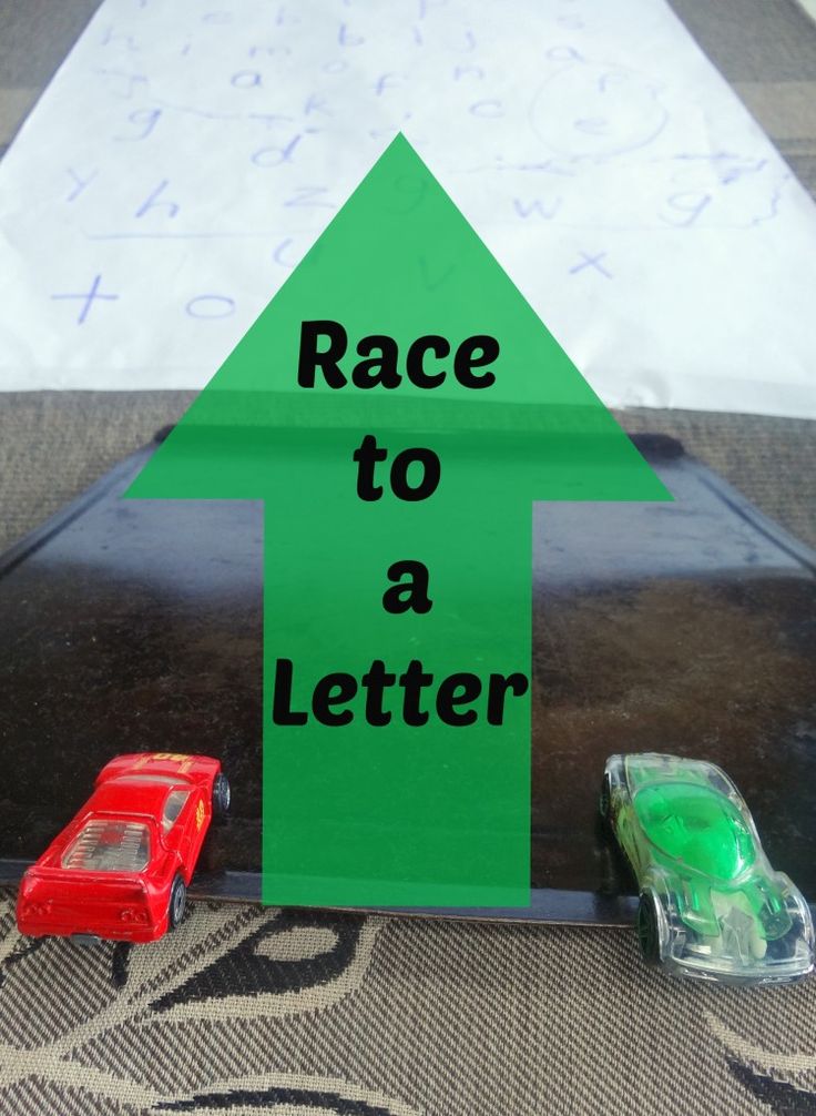 two toy cars sitting on top of a table next to a sign that says race to a letter