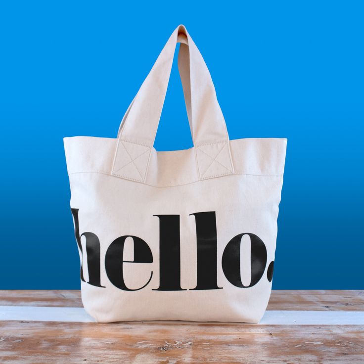 a white tote bag with the word hello on it sitting on a wooden table