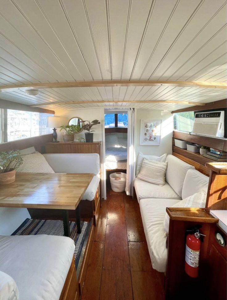 the inside of a camper with wood floors and white couches on it's sides