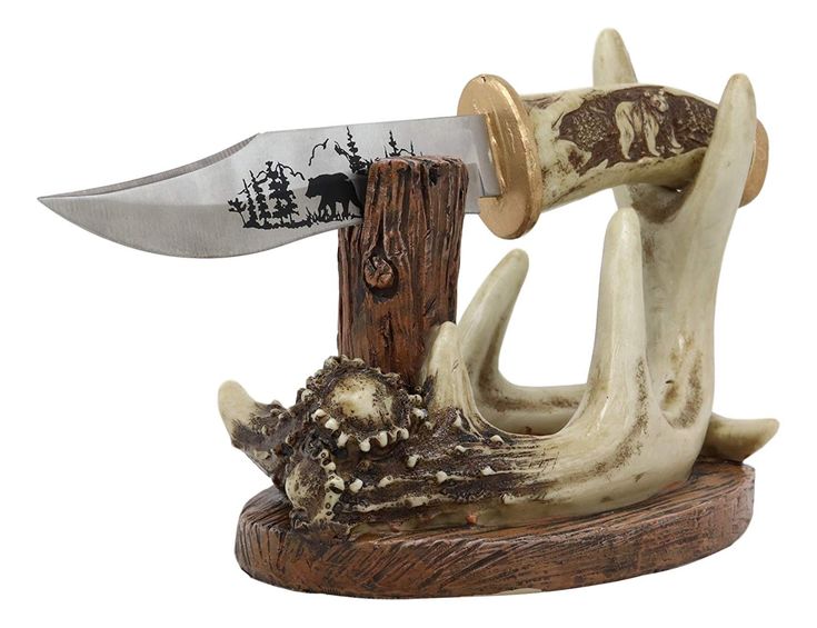 an antler with a knife sticking out of it's mouth sitting on top of a piece of wood