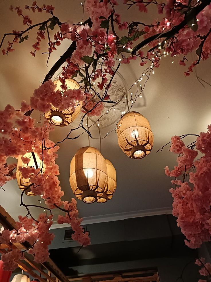 the lights are hanging from the ceiling in the room with cherry blossoms on it and pink flowers all around