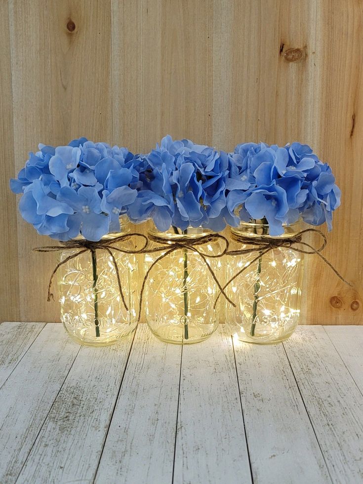 three mason jar vases with blue flowers in them