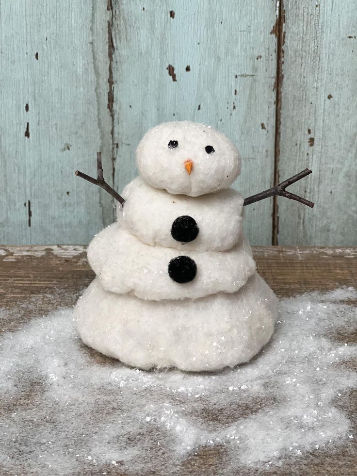 a snowman made out of wool sitting on top of some fluffy white foams