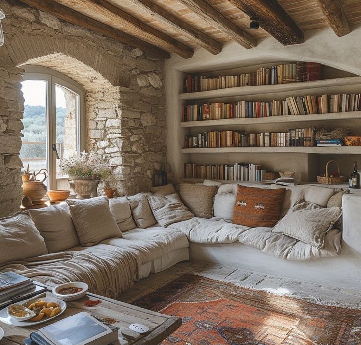 a living room filled with lots of furniture and bookshelves next to a window