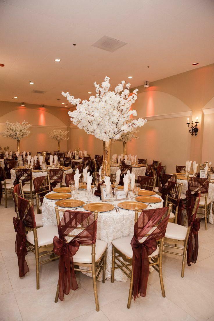 a room filled with tables and chairs covered in white tablecloths next to a chandelier