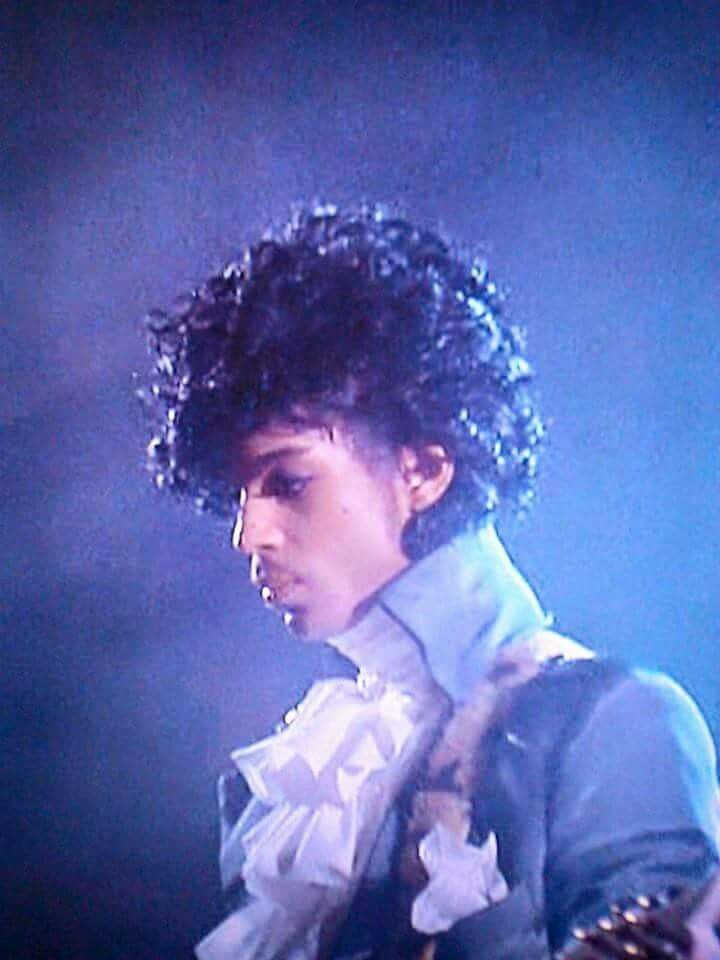 a man with curly hair holding a guitar