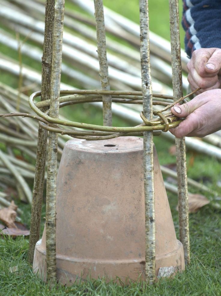 a person is working on an old bell in the grass with sticks and branches behind it