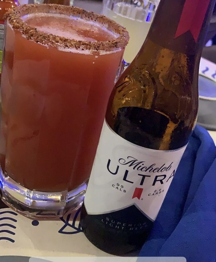 a bottle of alcohol next to a glass filled with liquid on a table in a restaurant