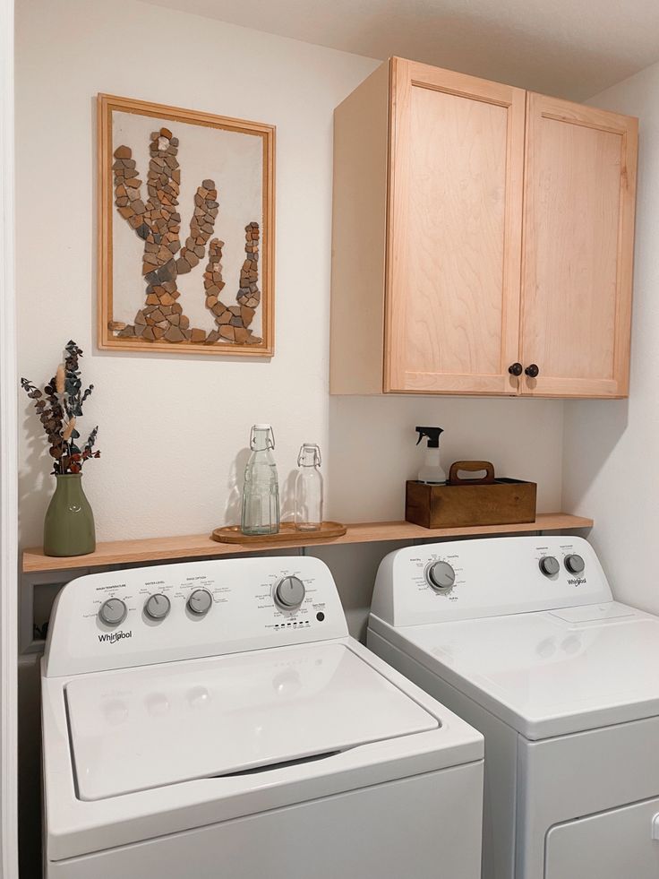 a washer and dryer in a small room with wooden cupboards on the wall