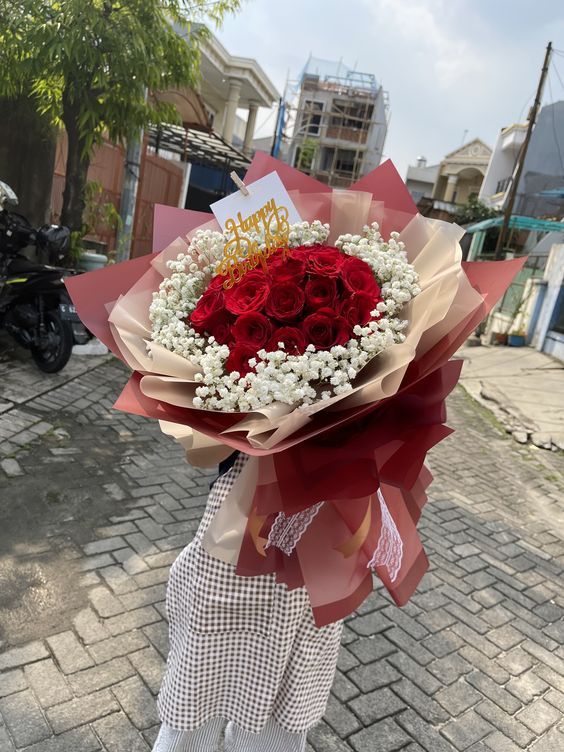 a person holding a bouquet of flowers on the street with buildings in the back ground