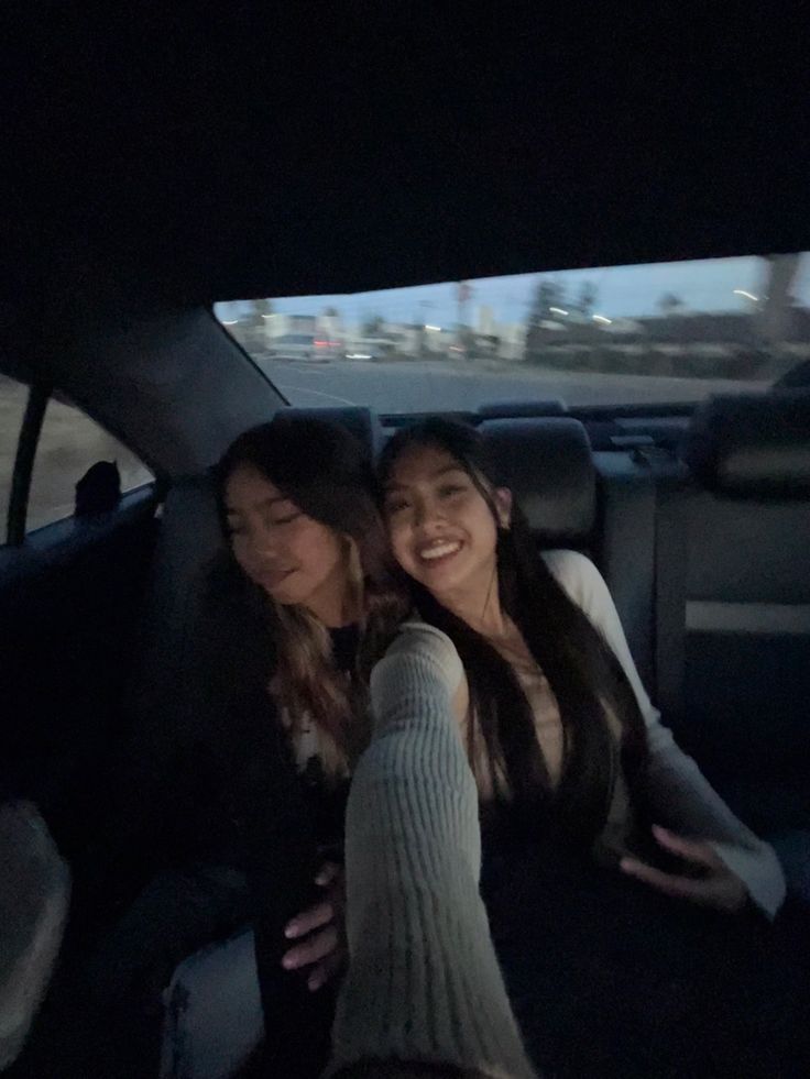 two women sitting in the back seat of a car