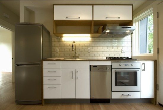 a kitchen with white cabinets and stainless steel appliances in the middle of wood flooring