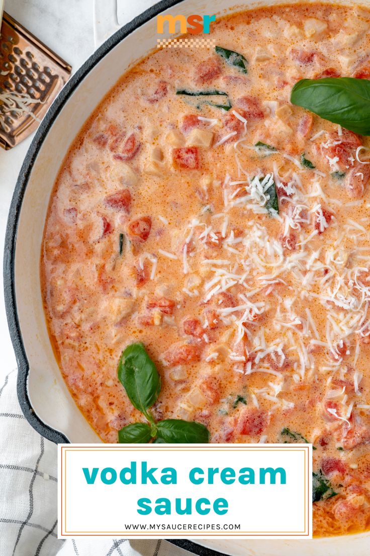 a bowl of vodka cream sauce with spinach leaves and cheese on top, in a pan