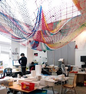 a room filled with desks and chairs covered in colorful streamers hanging from the ceiling