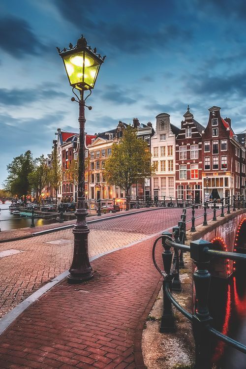 a street light sitting on the side of a brick road next to a body of water