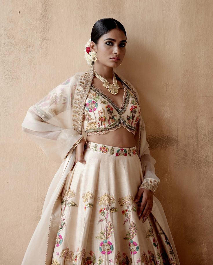 Editor's Note Presenting an opulent ivory raw silk lehenga set adorned with intricate floral thread embroidery and sumptuous velvet patchwork, elegantly highlighted with various embellishments. This captivating ensemble is paired with an embroidered blouse and dupatta, creating a regal and luxurious look perfect for grand occasions or elegant gatherings. The combination of the rich raw silk texture, the exquisite embroidery, and the ornate details on both the blouse and dupatta add a touch of op Lengha Inspiration, Floral Embroidery Lehenga, Floral Thread Embroidery, Embroidery Lehenga, Velvet Patchwork, Raw Silk Lehenga, Dresses Traditional, Indian Dresses Traditional, Party Wear Indian Dresses