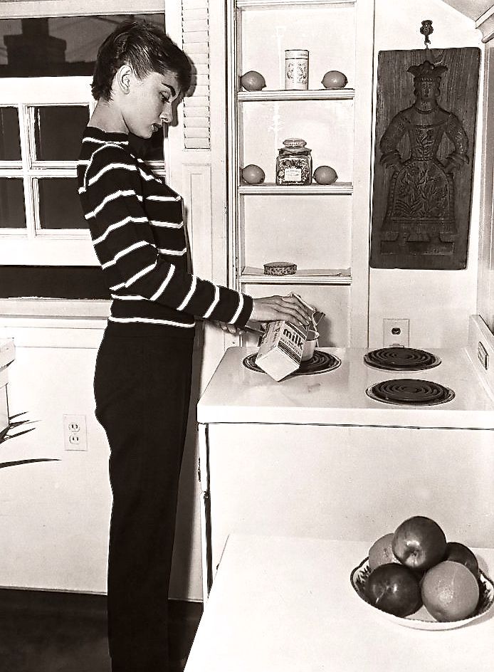 a young boy standing in front of an open refrigerator with fruit on the counter top