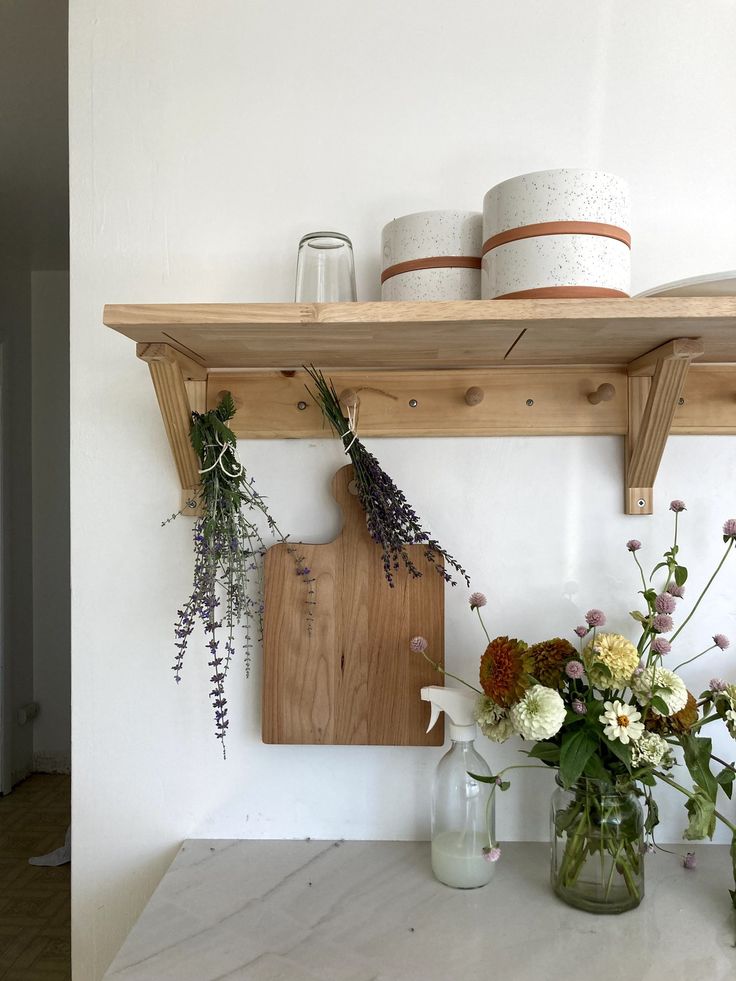 two vases filled with flowers sitting on top of a counter next to a cutting board