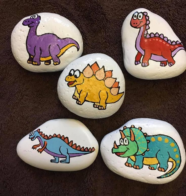 four painted rocks with dinosaurs on them