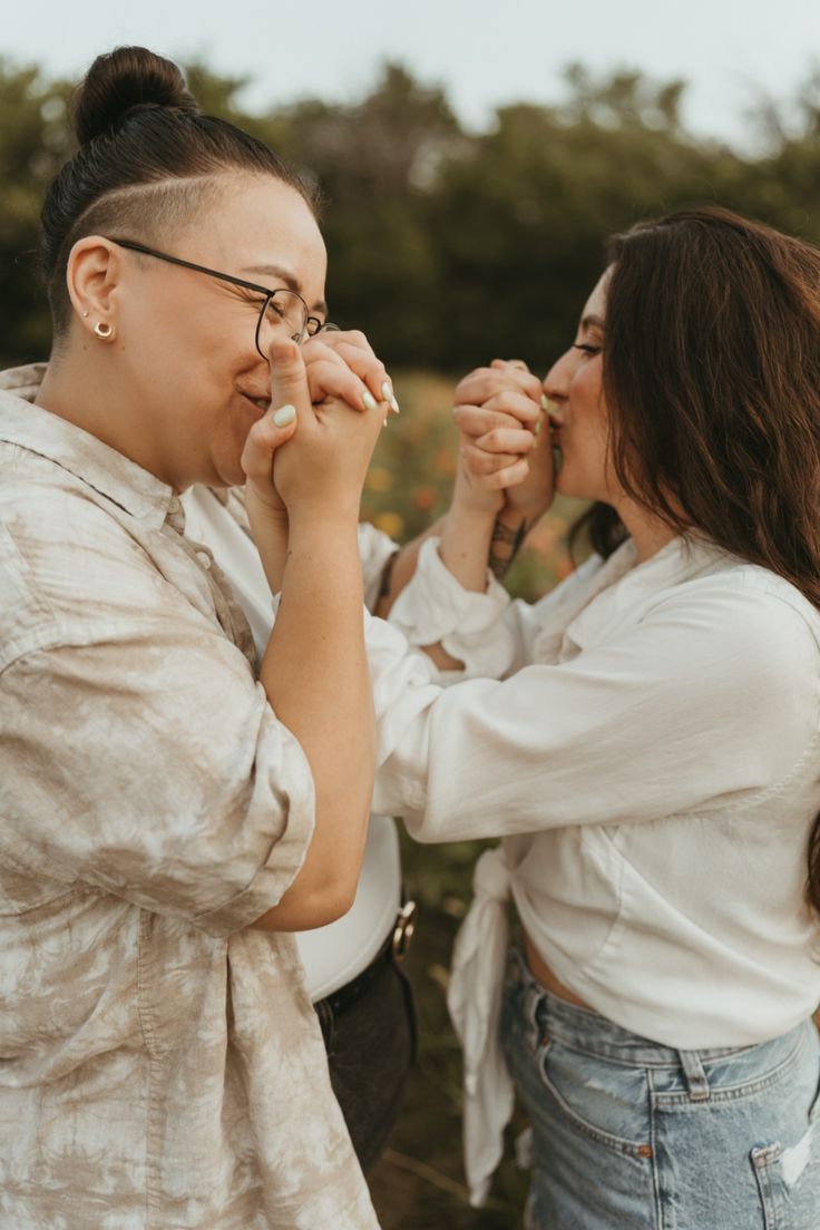 two women standing next to each other with their hands on one another's face