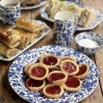 a table topped with blue and white plates filled with pastries on top of a wooden table