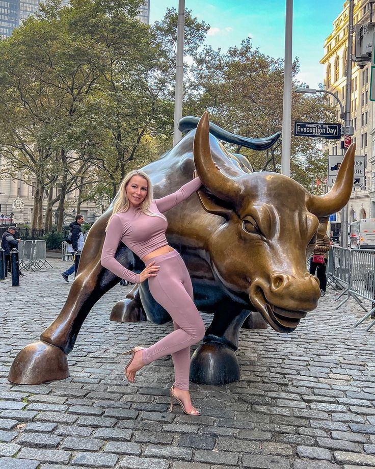 a woman posing in front of a statue of a bull