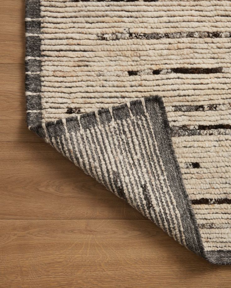 a close up of a rug on a wooden floor with a white and black area rug