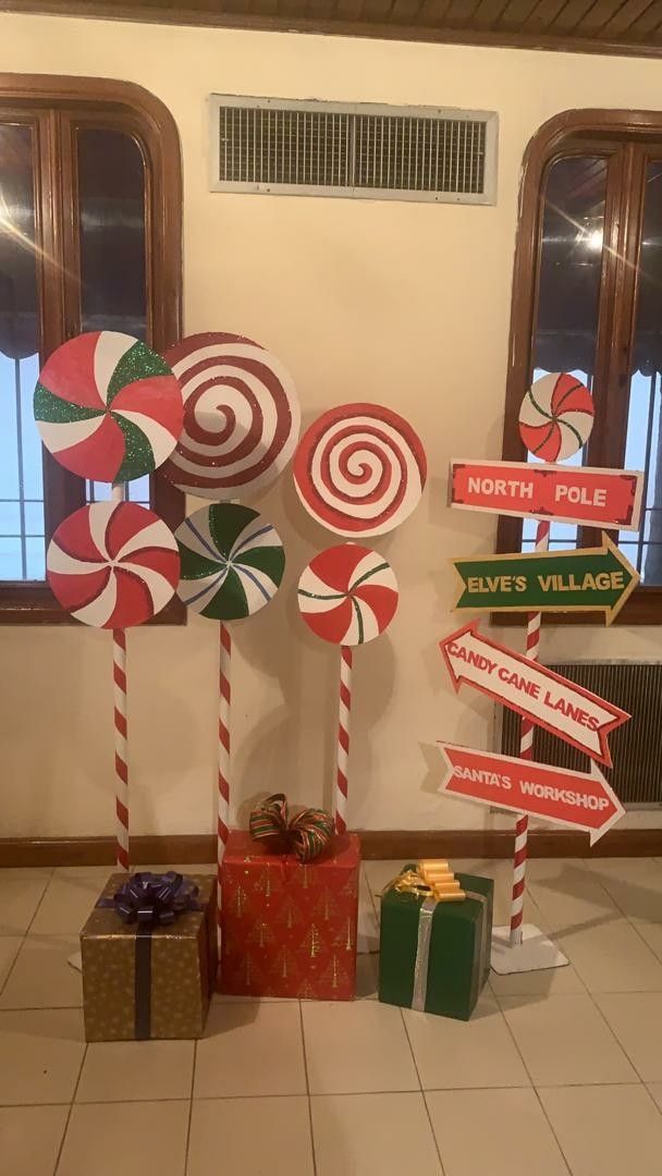 several candy canes are on display in front of a window with holiday signs and presents