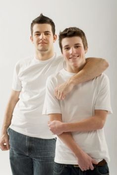 two men standing next to each other with their arms around one another and smiling at the camera