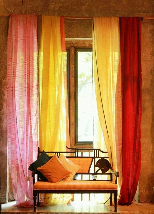 an orange and pink curtained room with a bench in the center, and a window behind it