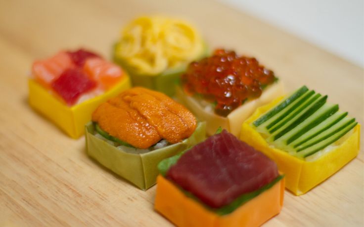 there are many different types of sushi on the wooden table, each with different toppings