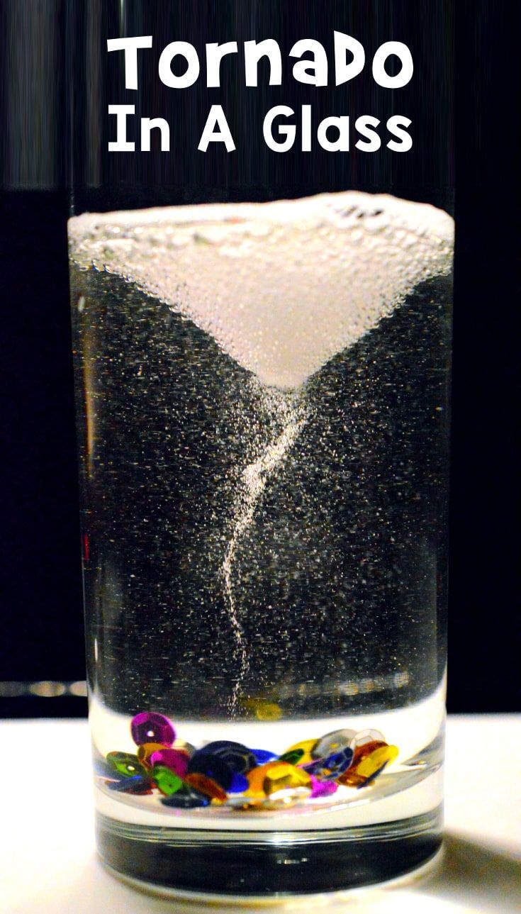 a glass filled with water and black sand