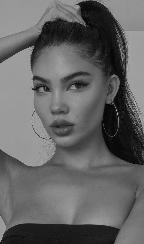 a woman with long hair and hoop earrings on her head, posing for the camera