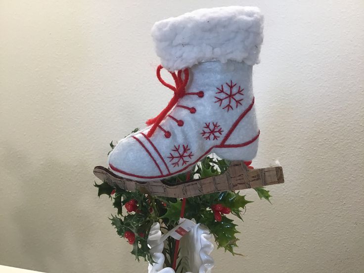 a pair of snow boots sitting on top of a wooden sled filled with holly