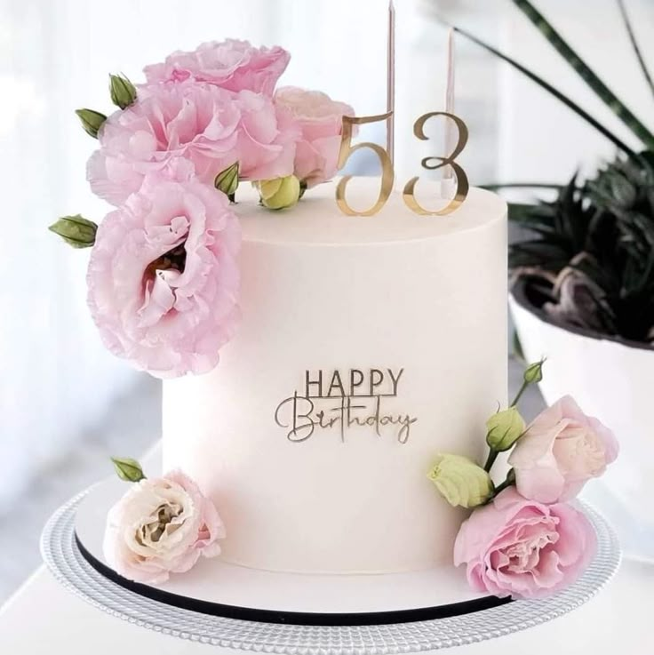 a white birthday cake with pink flowers and the number thirteen on it's side