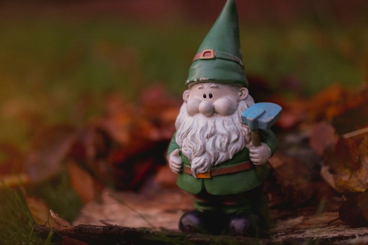 a small gnome figurine sitting in the leaves