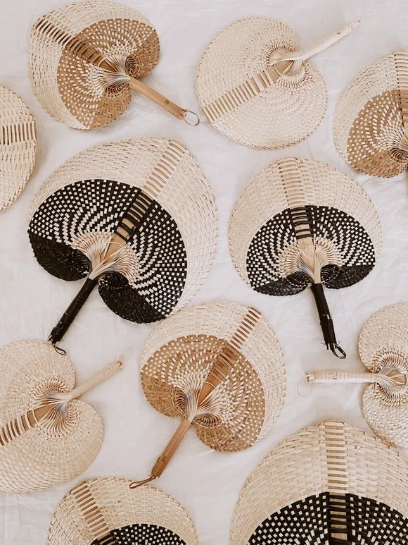 several woven fan shaped objects sitting on top of a white cloth covered table with black and white designs