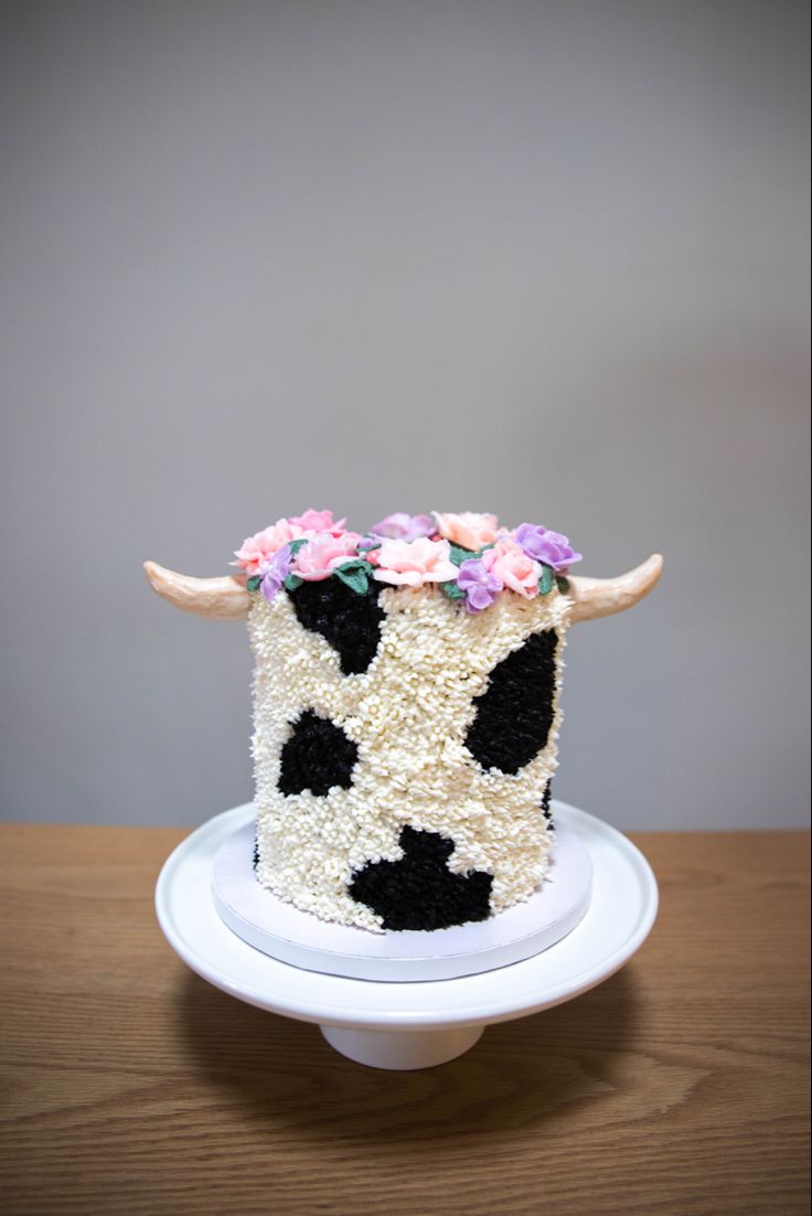 a cake decorated with flowers and a cow's head is on a white plate