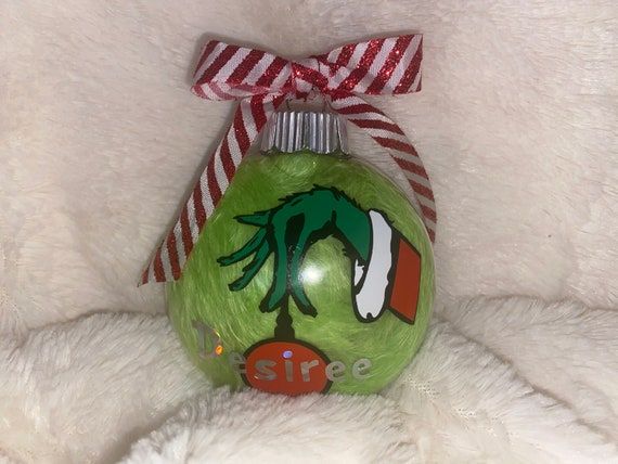 a green christmas ornament with a red and white striped ribbon