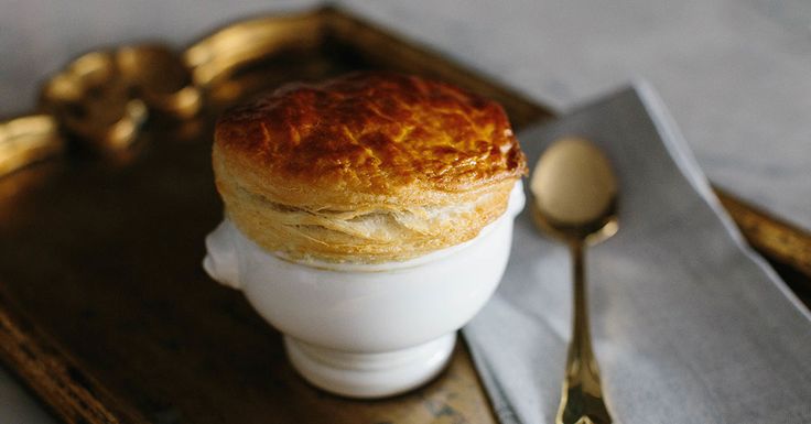 a close up of a pastry in a cup on a tray with gold spoons