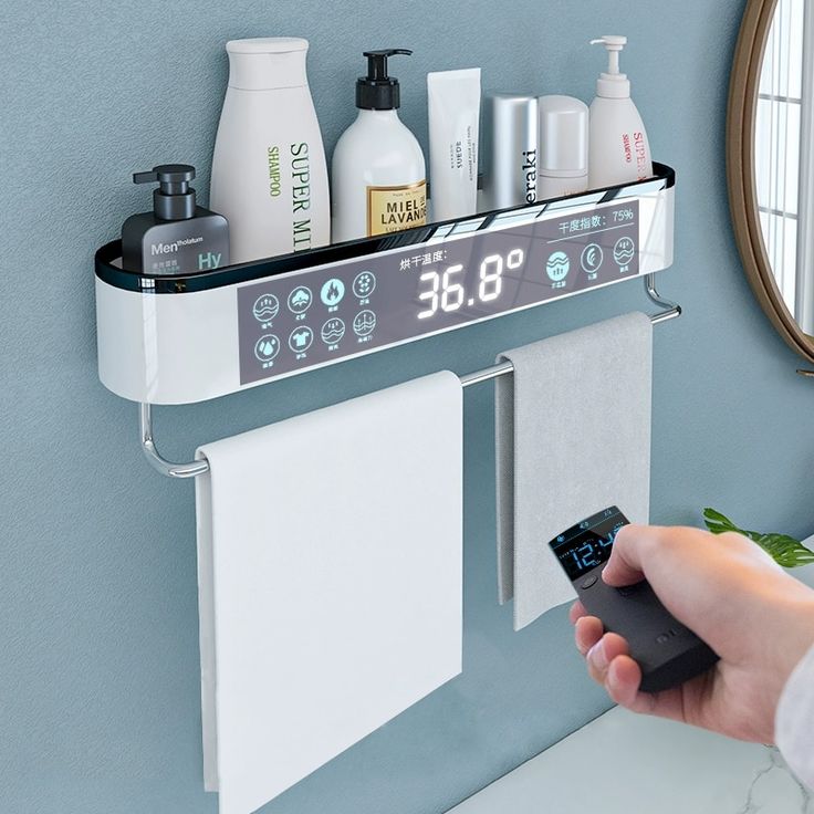 a person holding a remote control in front of a bathroom shelf with towels, soaps and lotion