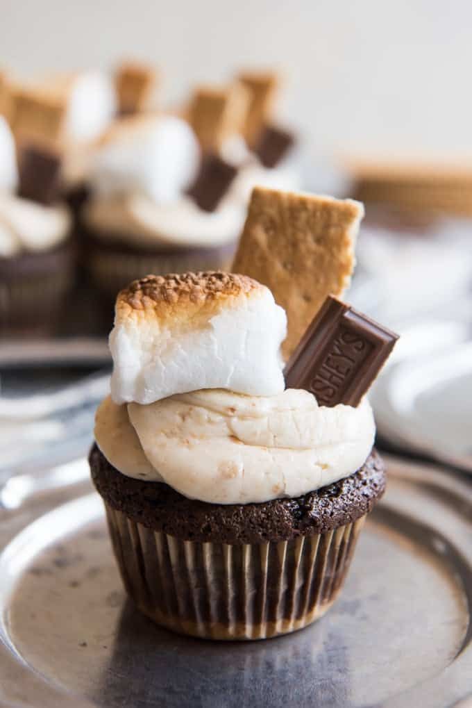 a cupcake with marshmallows and graham crackers on top sits on a plate