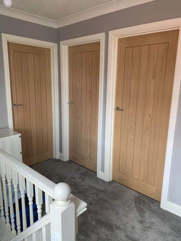 three wooden doors in a room with carpeted flooring and white handrails