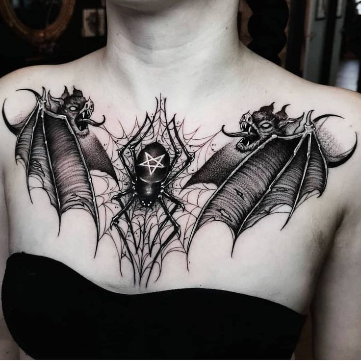 a woman with tattoos on her chest is wearing a black dress and has two bats attached to it