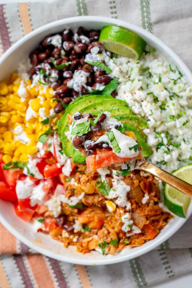 a white bowl filled with rice, beans, and avocado next to a lime