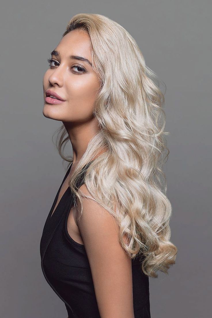 a woman with long blonde hair is posing for a photo in front of a gray background