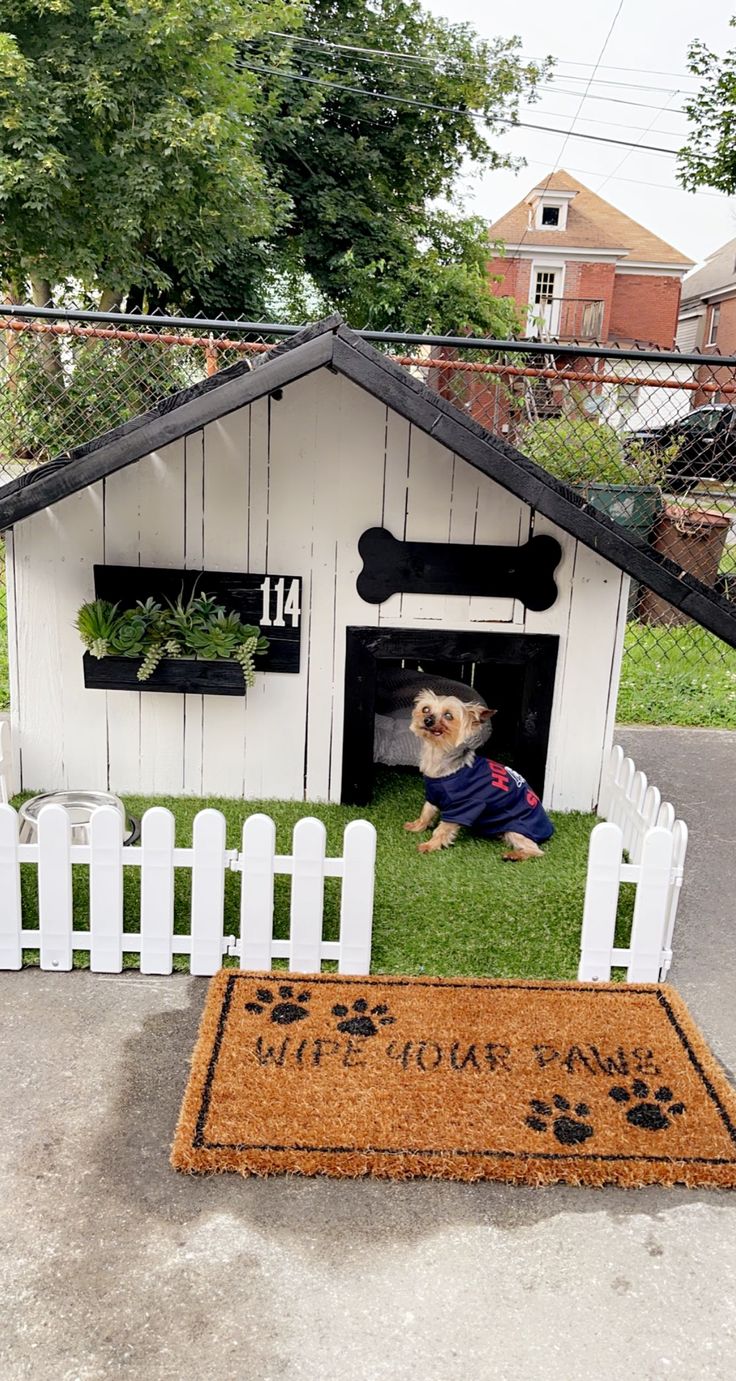 a dog is sitting in his kennel on the grass with it's door open